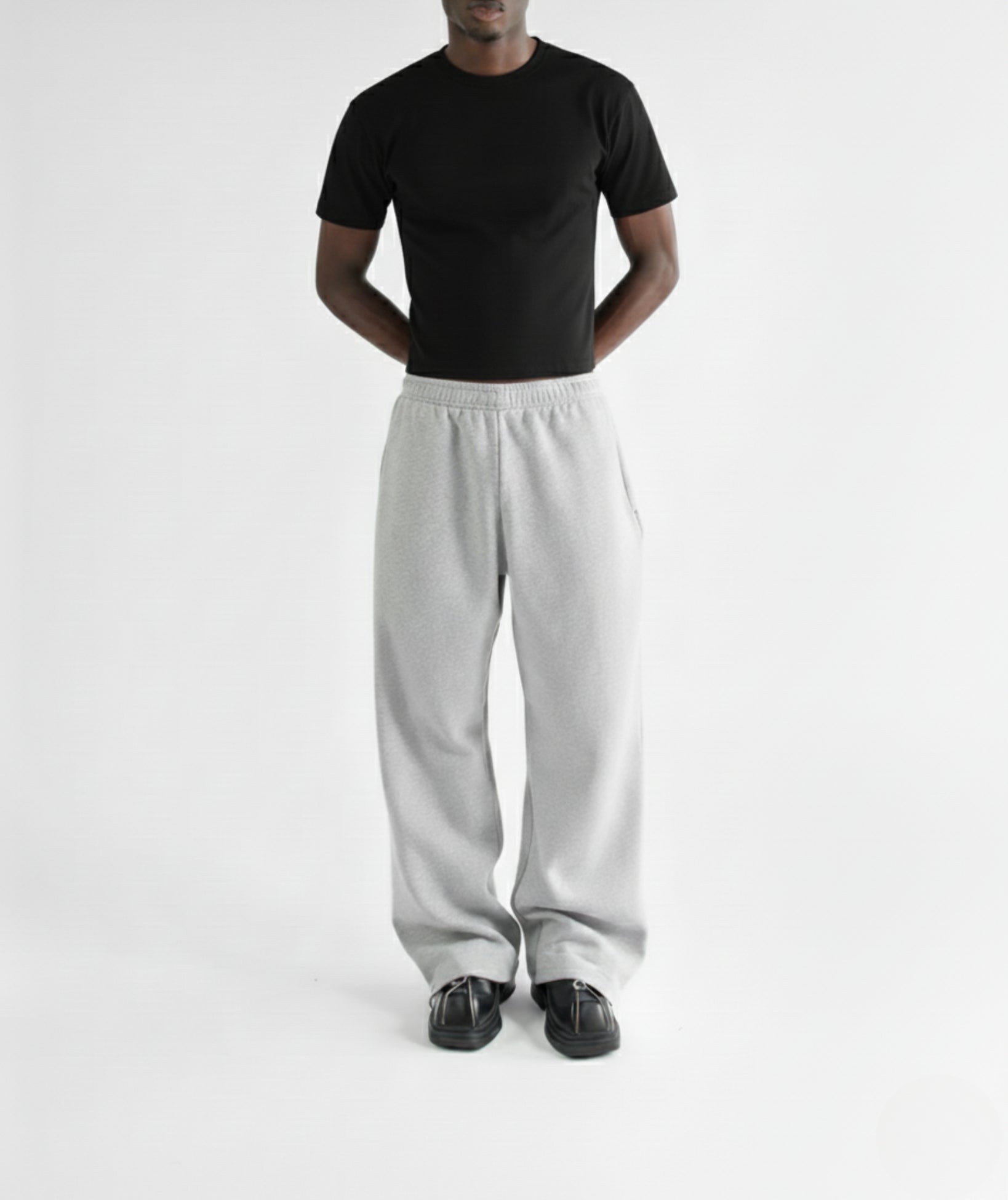 Model standing with hands in pockets, wearing marl gray straight-leg sweatpants with fitted black tshirt to show the relaxed fit and drape