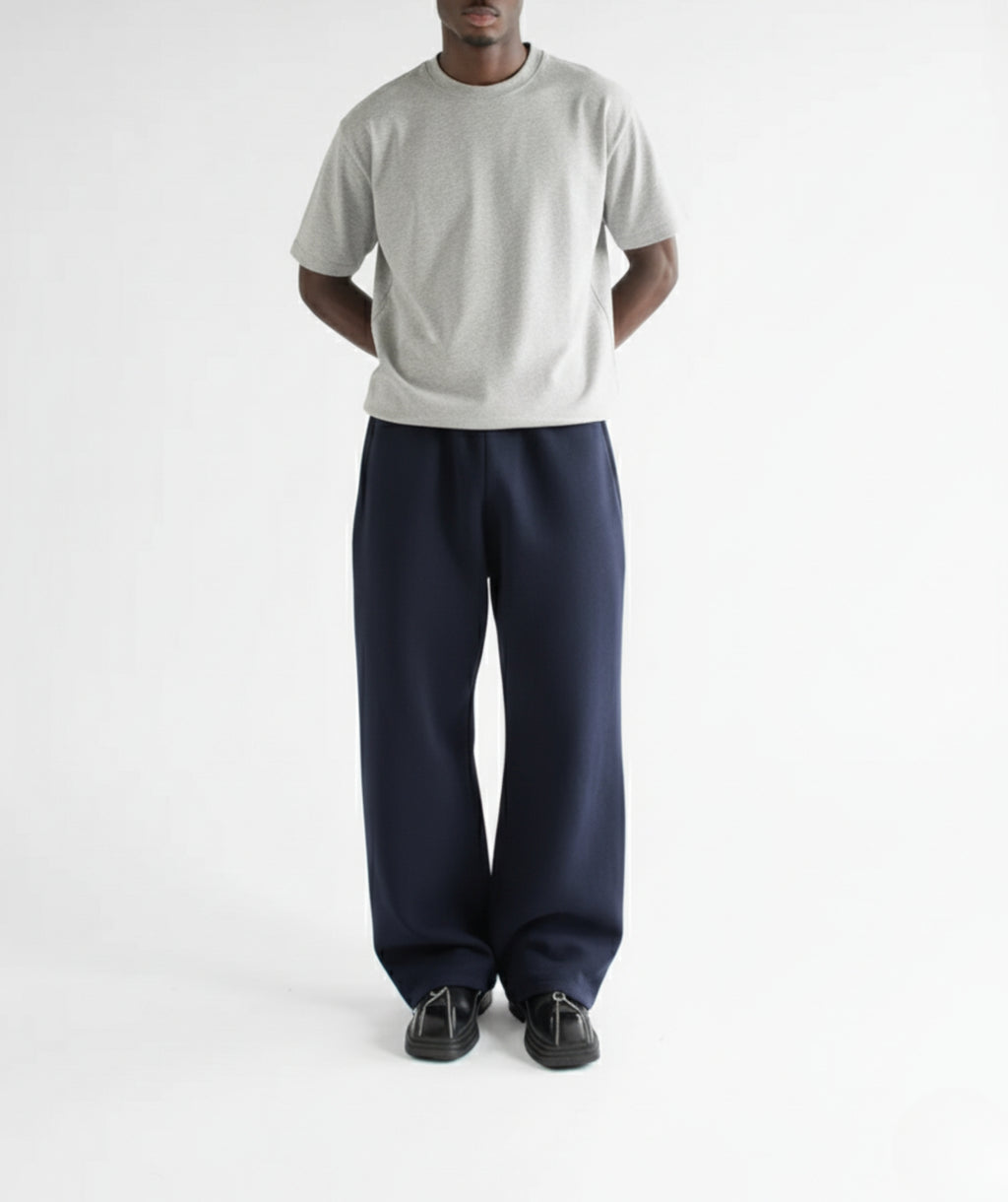 Model standing with hands in pockets, wearing navy straight-leg sweatpants to show the relaxed fit and drape.
